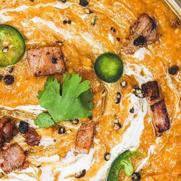 Close-up shot of the Bacon & Jalapeño Soup, emphasizing the texture and vibrant colors. The creamy pumpkin base is accented by crispy bacon pieces and jalapeño slices for a mouthwatering presentation.