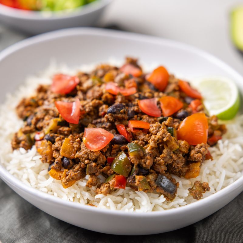 Close-up shot of the Burrito Bowl, emphasizing the rich colors and textures of the dish. The seasoned beef, zesty black beans, crisp corn, and vibrant capsicum are shown in stunning detail, highlighting the fresh and wholesome ingredients.