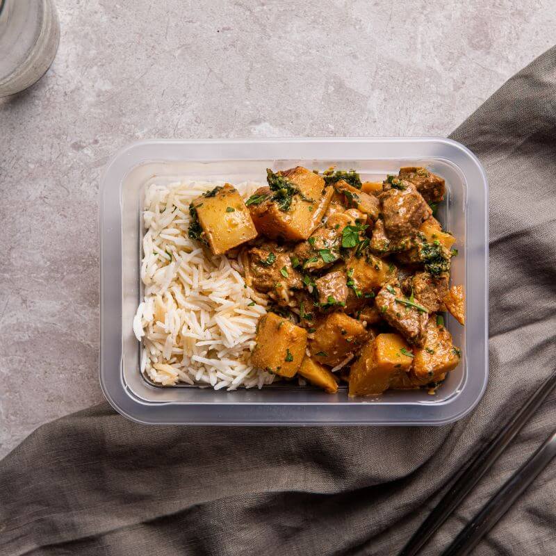 Clear container shot of the Beef Massaman, showcasing the meal in its packaging. 