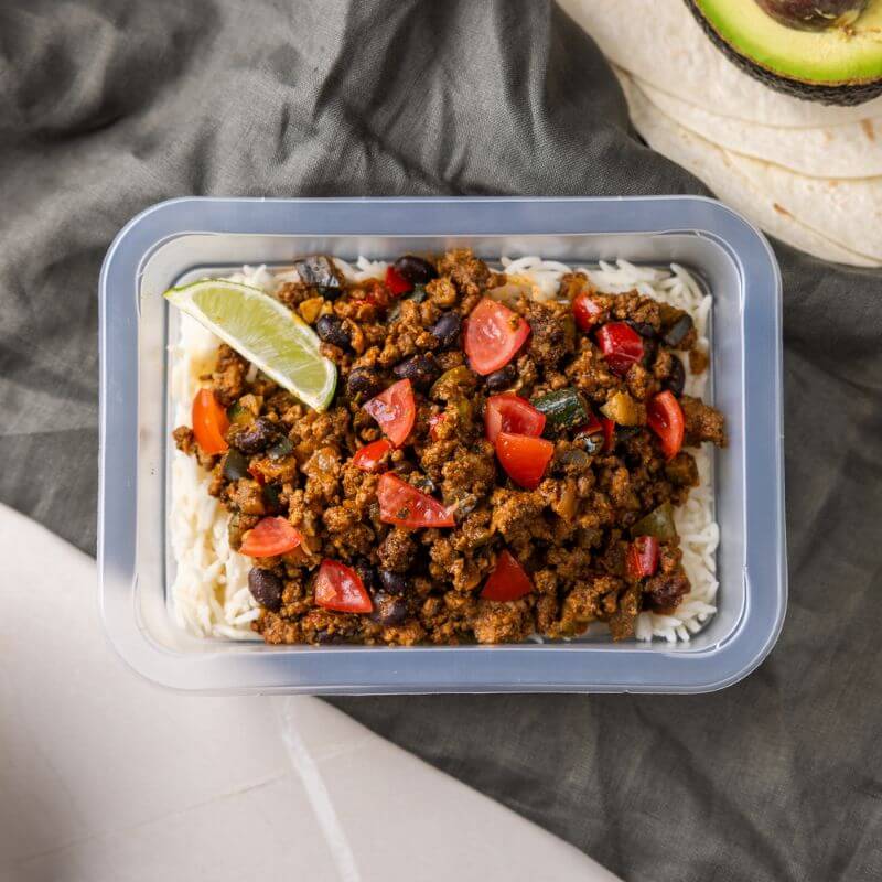 Clear container shot of the Burrito Bowl, perfectly packed and ready for convenience. The vibrant ingredients—beef, capsicum, black beans, and corn—are visible through the container, showcasing the freshness and appeal of the dish.