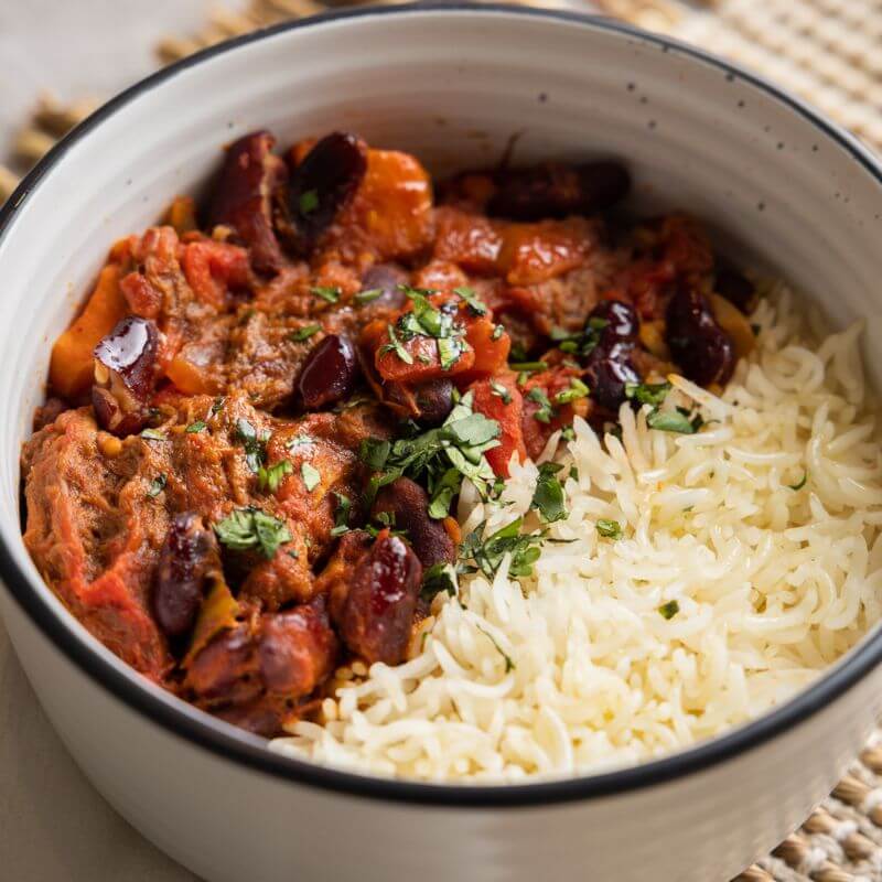 Close-up of Texas Brisket Chilli, focusing on the rich, tender brisket, poppin' beans, and vibrant vegetables, with a hint of parsley garnish.