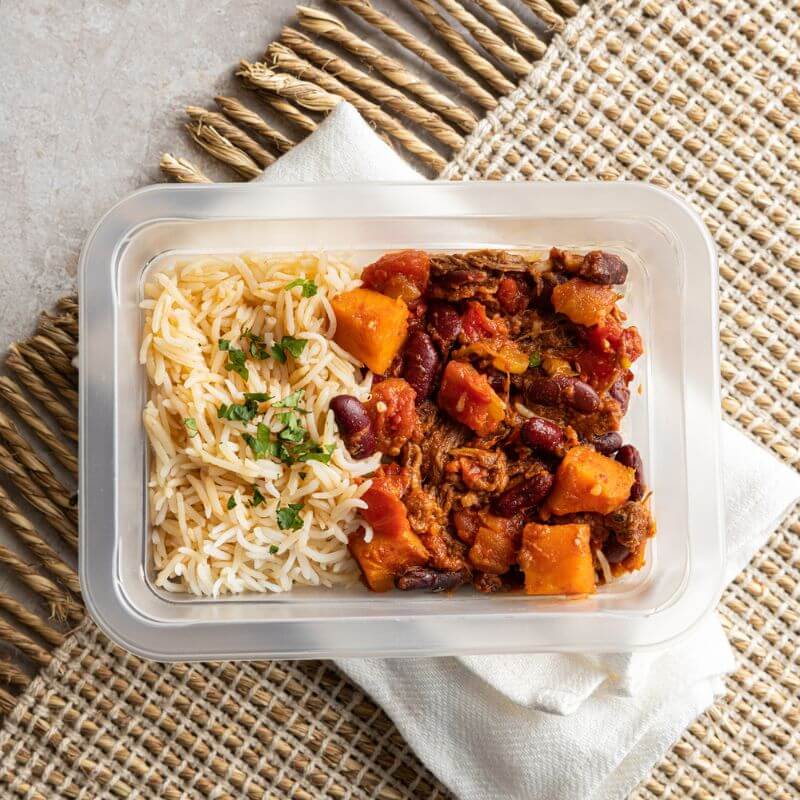 Side shot of Texas Brisket Chilli, with the same elements as in previous photos, highlighting the meal in its rustic setting with parsley garnish on top.