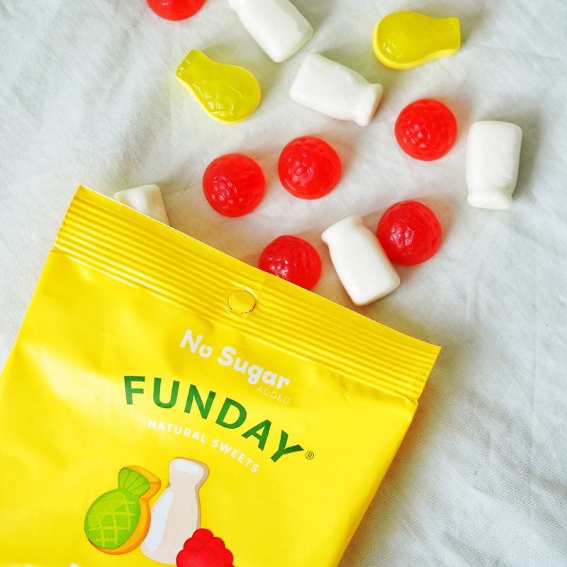 A top down photograph of an open packet of gummy lollies disaplayed on a white cloth to show the different types of gummies coming out of the packaging.