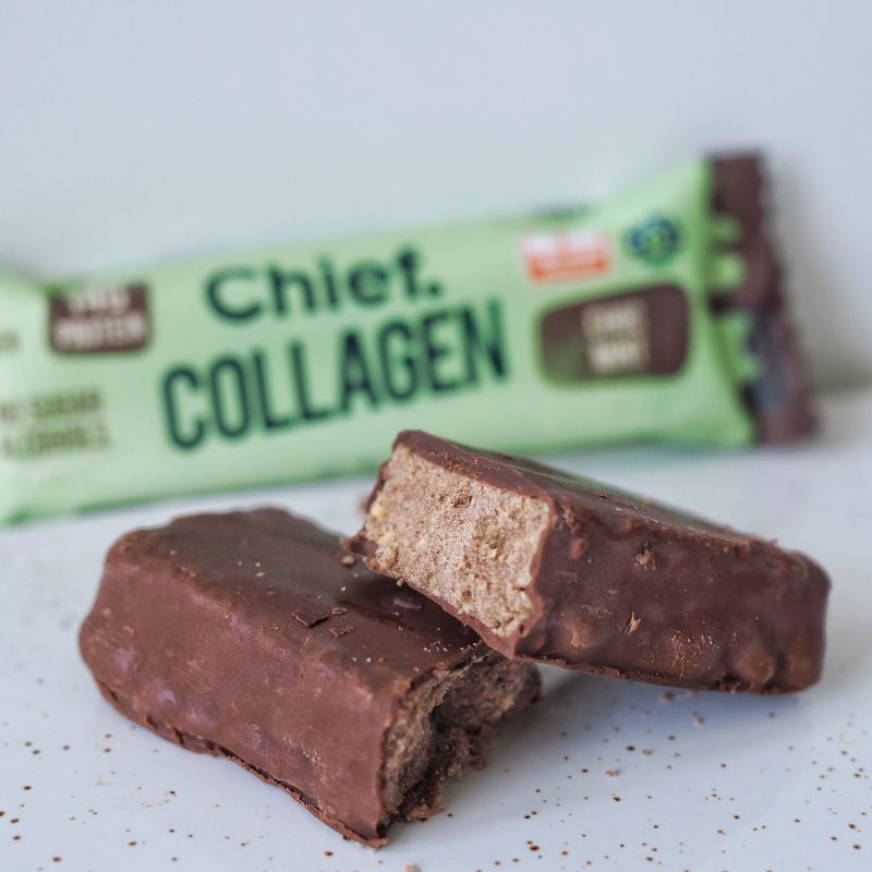 A side angle photograph of a cut in half chocolate mint collagen protein bar with the packaging in the background.