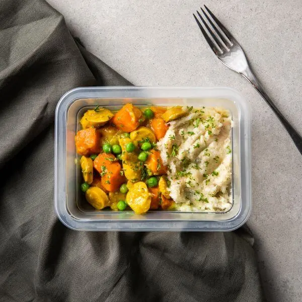 Container shot of curried sausage with cauliflower mash, presenting the meal in a neat, well-lit container with a simple background for a clean and polished look.